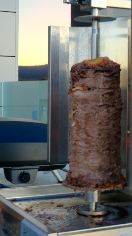 Gyro meat on a vertical spit at a Bora outdoor event